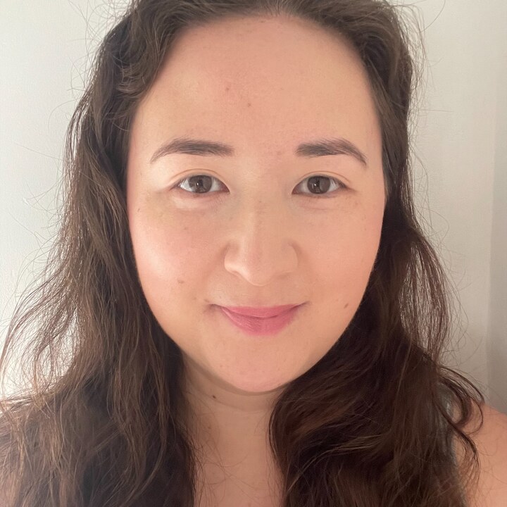 Smiling person with long brown hair and a grey top