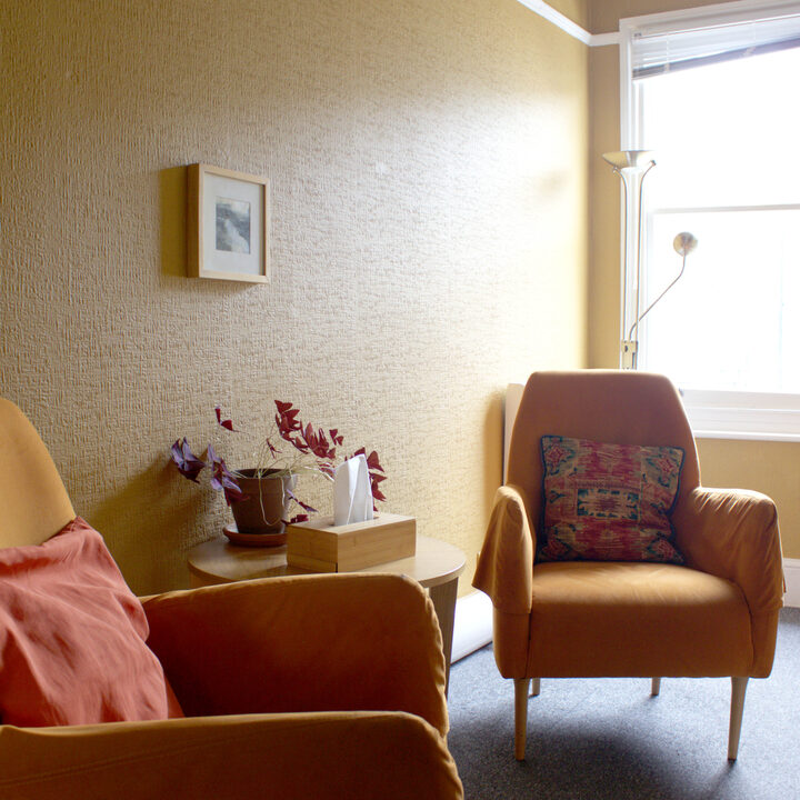 A green therapy room with colourful chairs