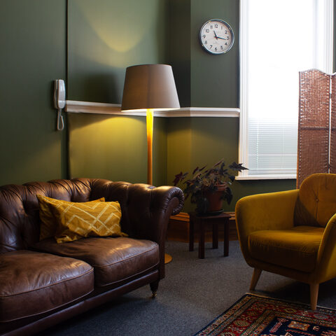 Olive room with a green wall, leather sofa and mustard armchair